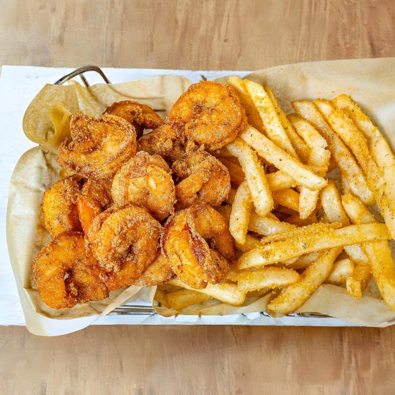 A basket of MiMi's Craft Kitchen's crispy fried shrimp and seasoned french fries.