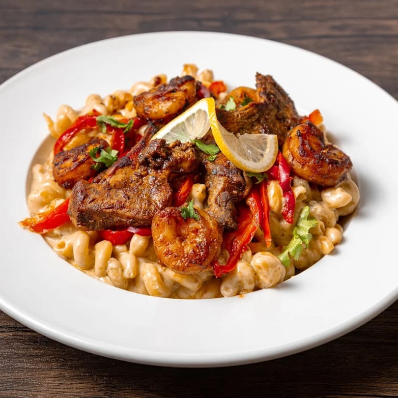 MiMi's Craft Kitchen's American dish with grilled chicken, shrimp, red peppers, and lemon slices over pasta.