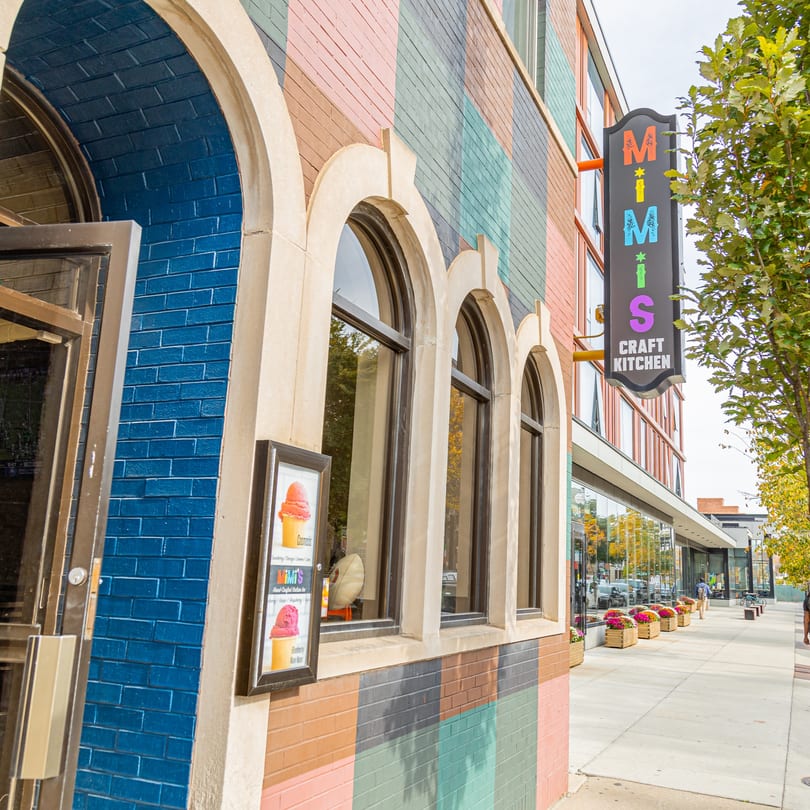 MiMi's Craft Kitchen exterior with a colorful brick facade, arched windows, and a prominent sign.